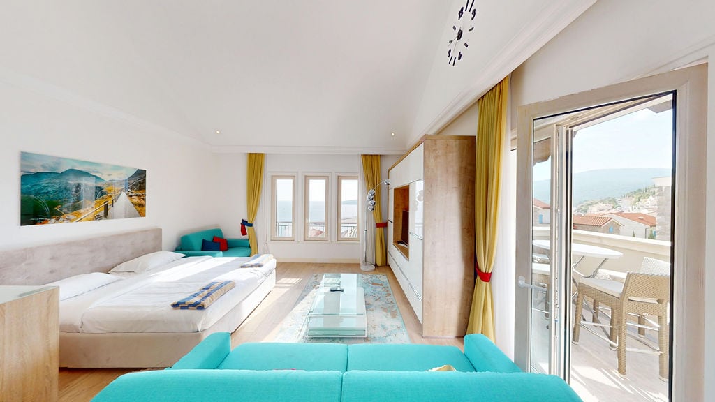 Bright bedroom with sea view in Krašići residential complex, Montenegro: double bed, turquoise sofa, and terrace access.