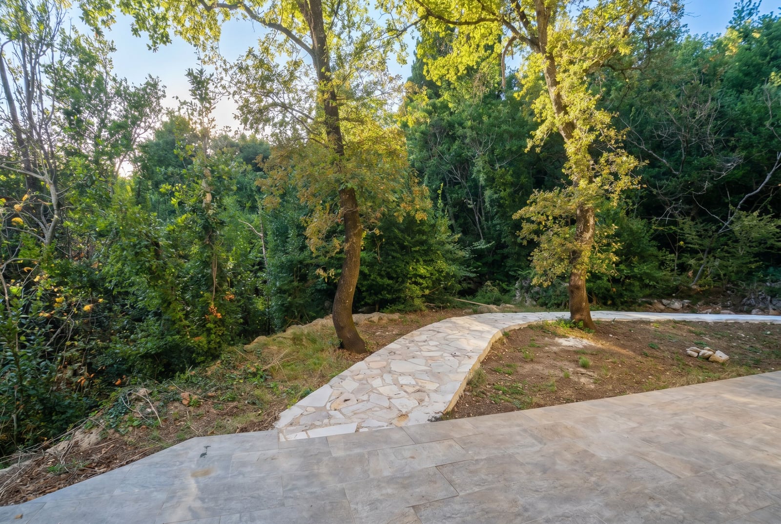 Stone path in a green garden of a residential complex in Herceg Novi, Montenegro, view of the wooded area by the house.