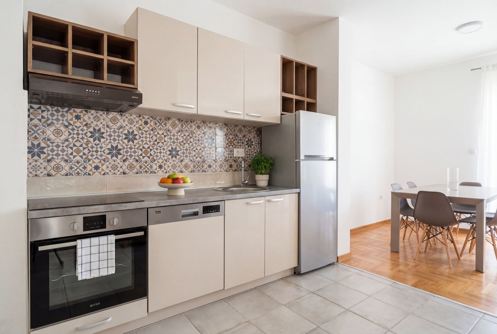 Modern kitchen with appliances and dining area in an apartment, Budva, Montenegro. Bright interior with patchwork tile.