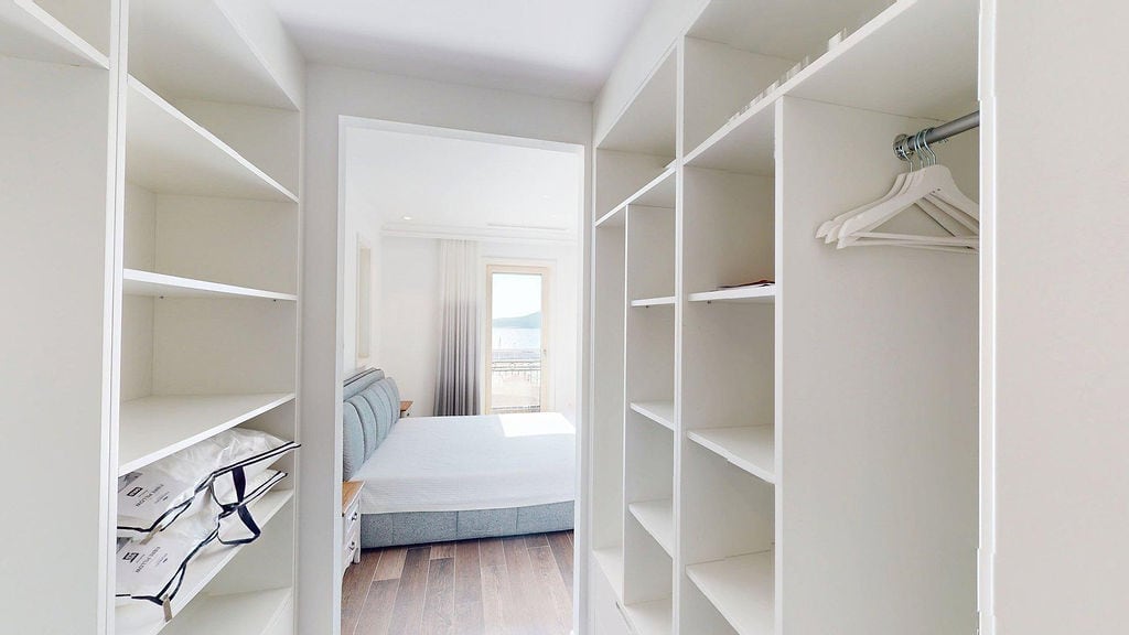 White dressing room and bedroom with a sea view in an apartment, Luštica, Montenegro. Modern interior.