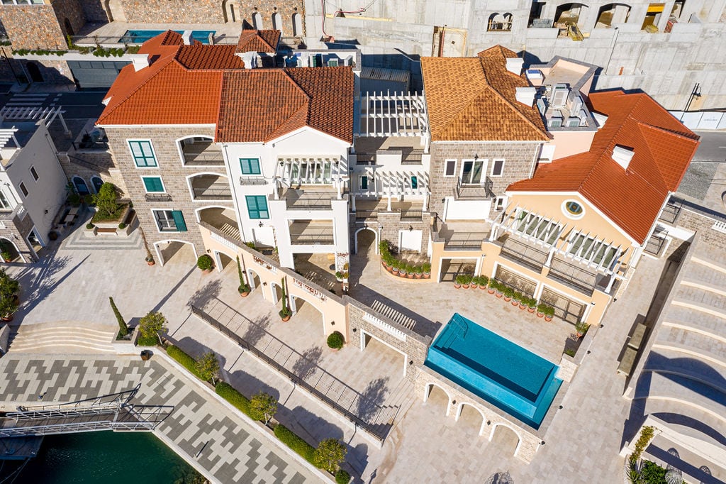 Aerial view of a luxury residential complex in Luštica, Montenegro: stone cladding, terraces, and an outdoor swimming pool.