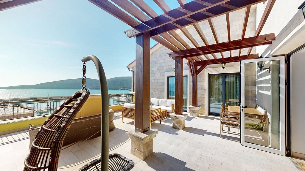 Spacious terrace with a pergola and sea view in the Luštica residential complex, Montenegro: wicker furniture and a lounge area.