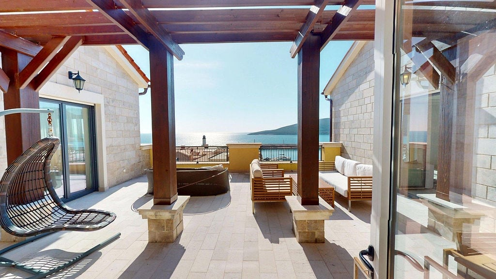 Terrace with a wooden pergola and sea view in the Luštica residential complex, Montenegro: wicker furniture and sofas.