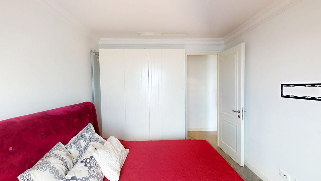 Bedroom with a red bed and white wardrobe in an apartment, Luštica, Montenegro. Modern interior of a residential complex.