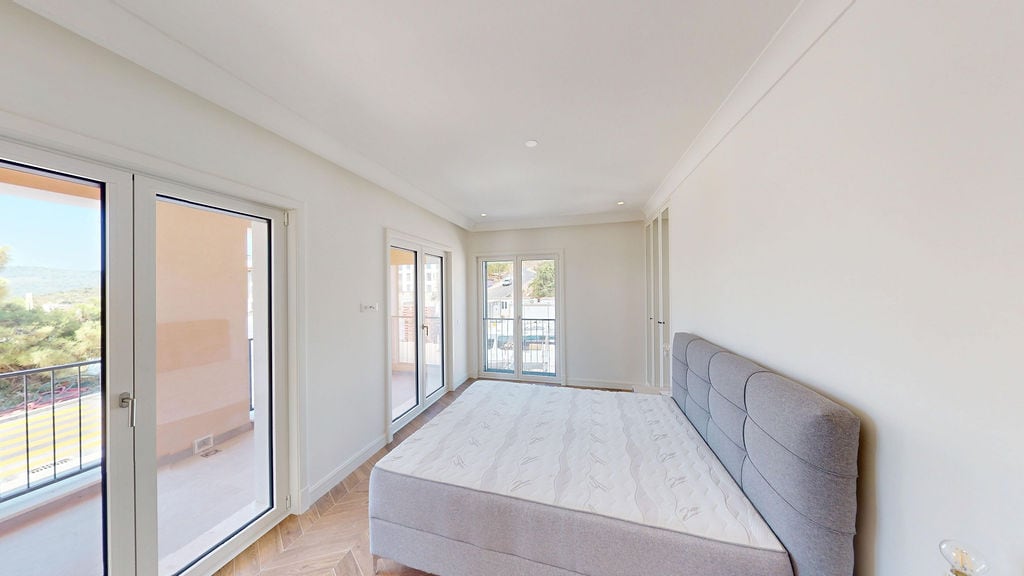 Bright bedroom with a double bed in an apartment in Luštica, Montenegro, with access to a terrace and a view of nature.