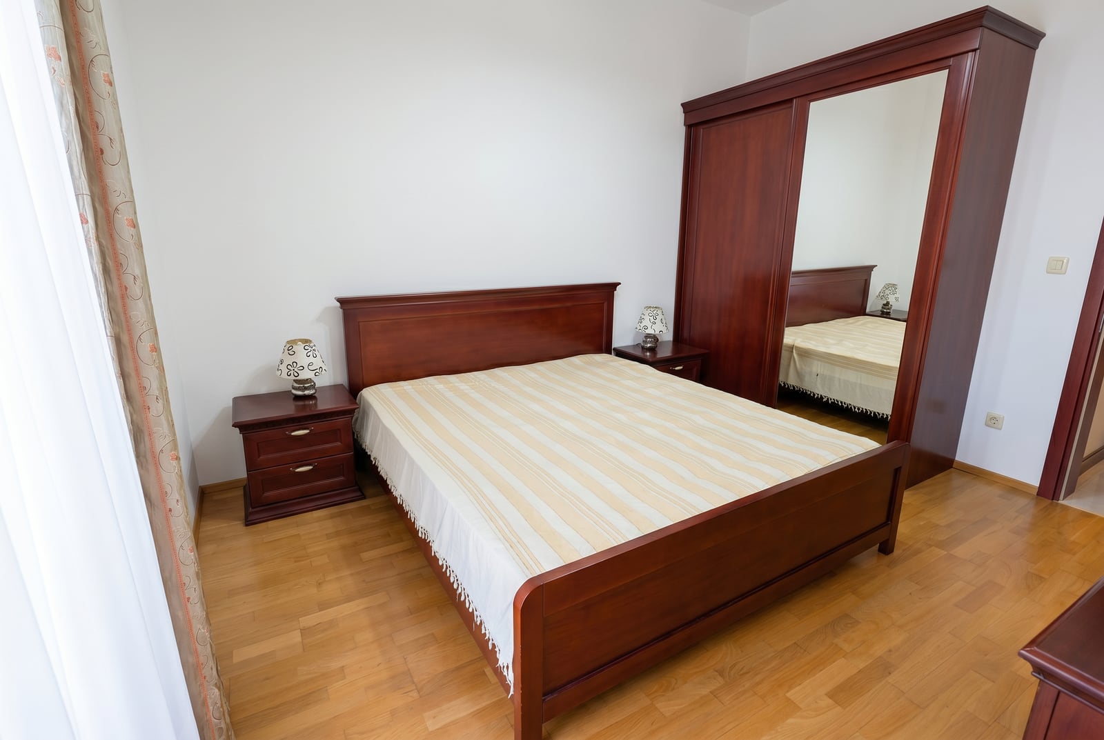 Bedroom with a double bed and dark wood wardrobe in an apartment for sale in Bečići, Montenegro.