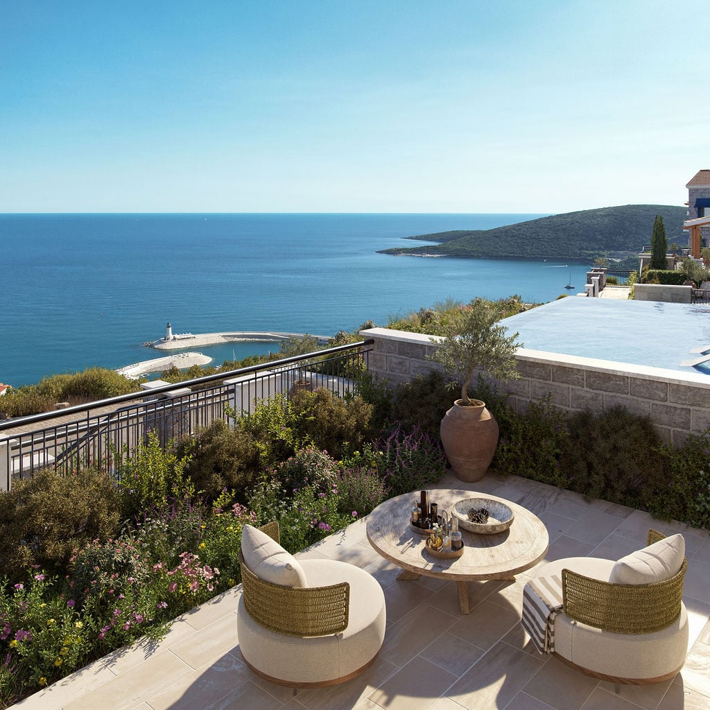 Terrace with pool and sea view in Lustica Bay, Montenegro: wicker furniture, stone finishes, and panoramic scenery.