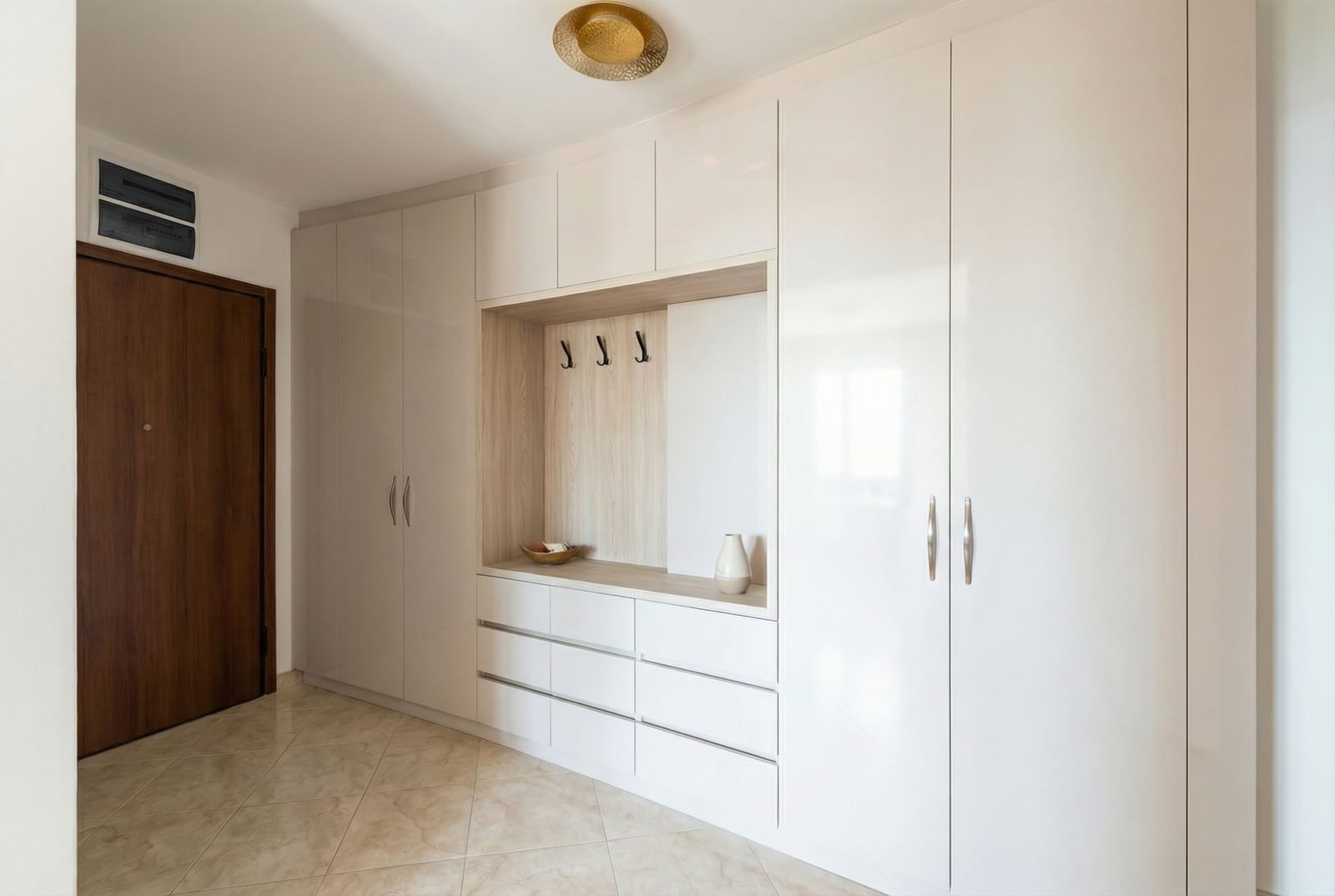 Built-in white wardrobe with a niche and drawers in the apartment hallway, Rafailovići, Montenegro. Modern interior.