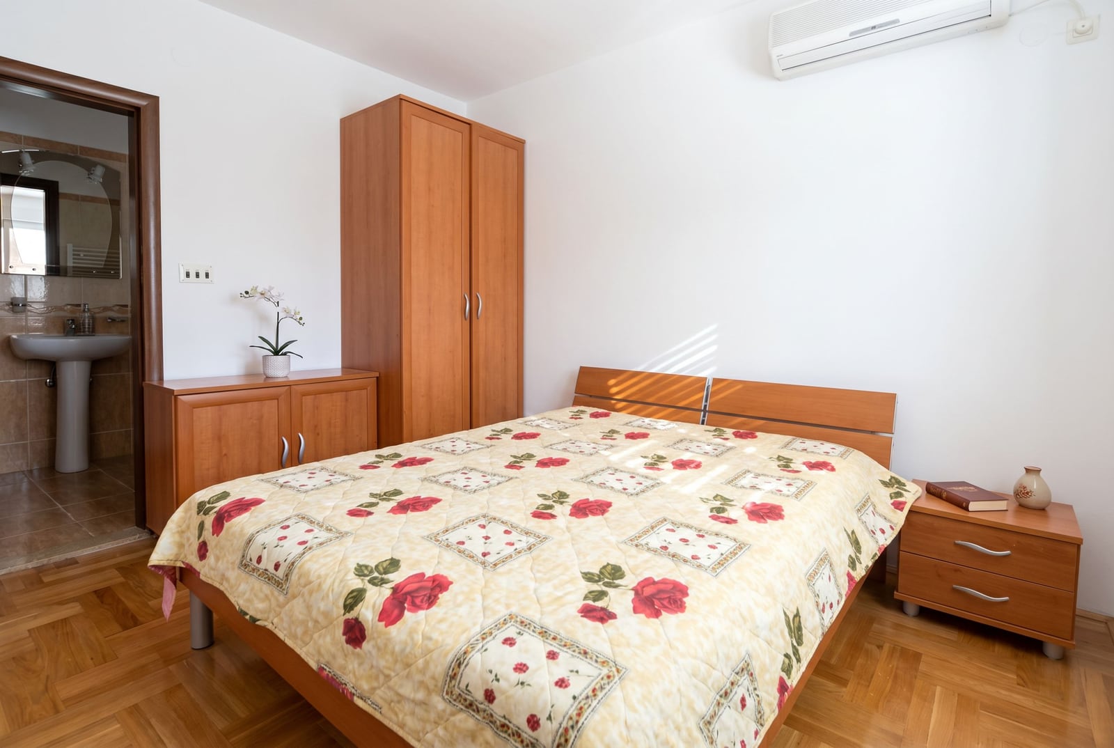 Bedroom with a double bed and wooden furniture in a house, Baošići, Montenegro. View of the bathroom.