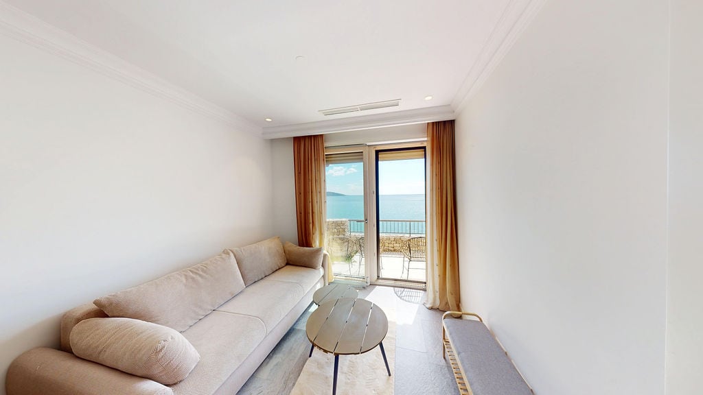 Living room with a beige sofa and sea view in the Luštica residential complex, Montenegro. Modern interior with a terrace.