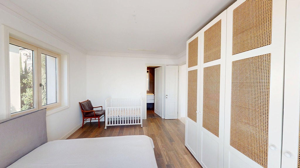 Bright bedroom with a crib and wardrobe in the Lustica Bay apartment, Montenegro: modern interior, view from the window.