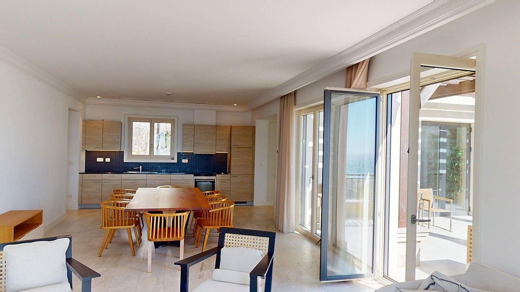 Living room with kitchen in an apartment in Luštica, Montenegro: modern furniture, dining area, and access to a terrace with a sea view.