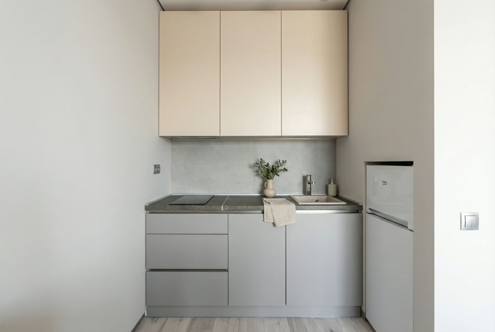 Moderne kompakte Küche in einer Wohnung in Bečići, Montenegro: helle Fronten, Einbaugeräte und eine Steinarbeitsplatte.