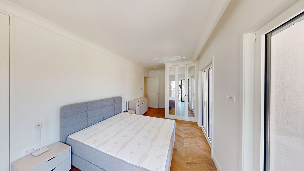 Bright bedroom with a double bed and mirrored wardrobe in an apartment in Luštica, Montenegro. Parquet flooring.