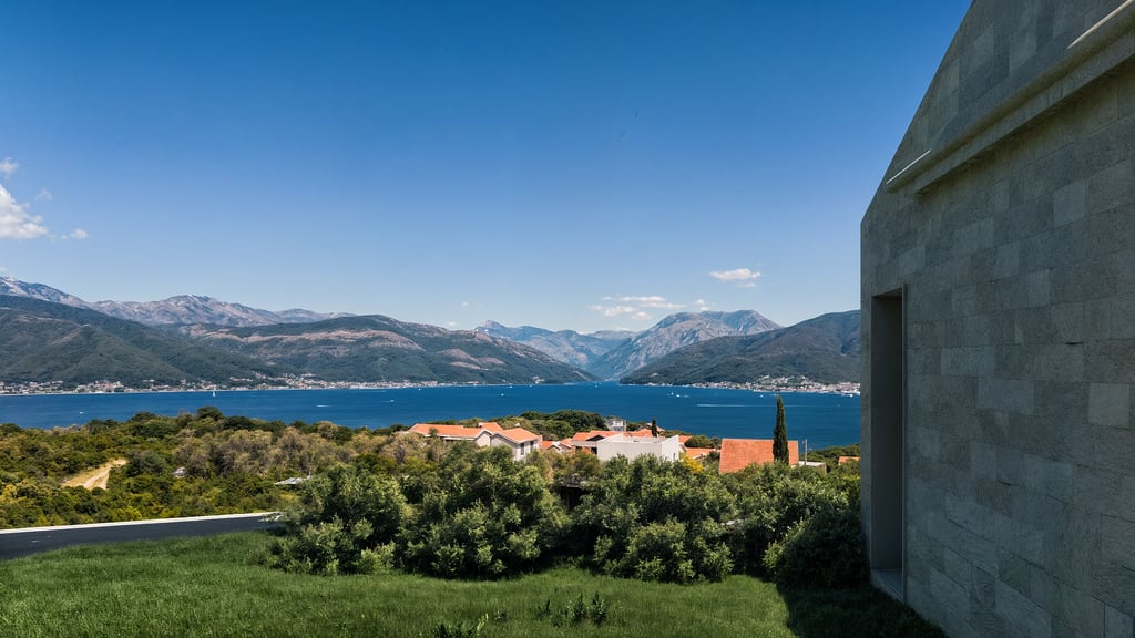 Panoramic view of the Bay of Kotor and mountains from a modern villa in Luštica, Montenegro, stone building facade.