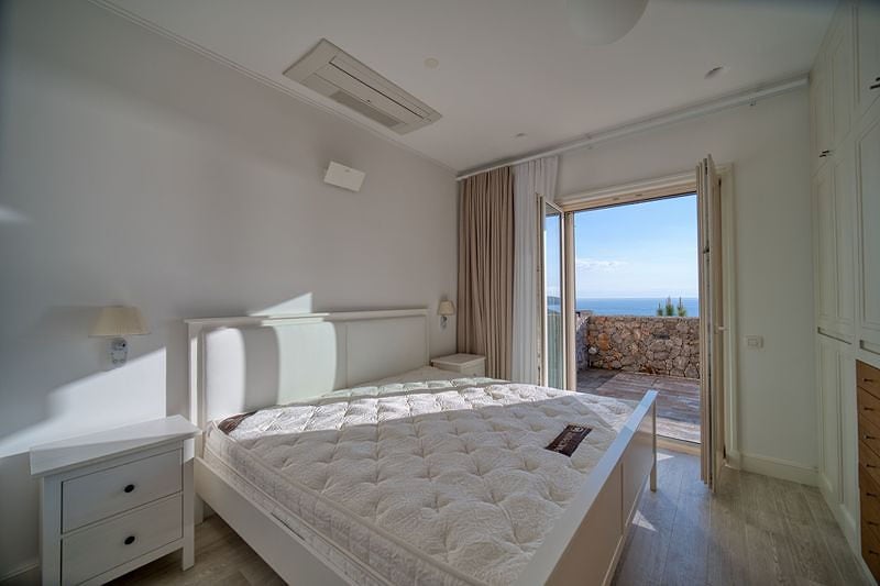 Bright bedroom with a double bed and access to a terrace with a sea view in the Luštica residential complex, Montenegro.
