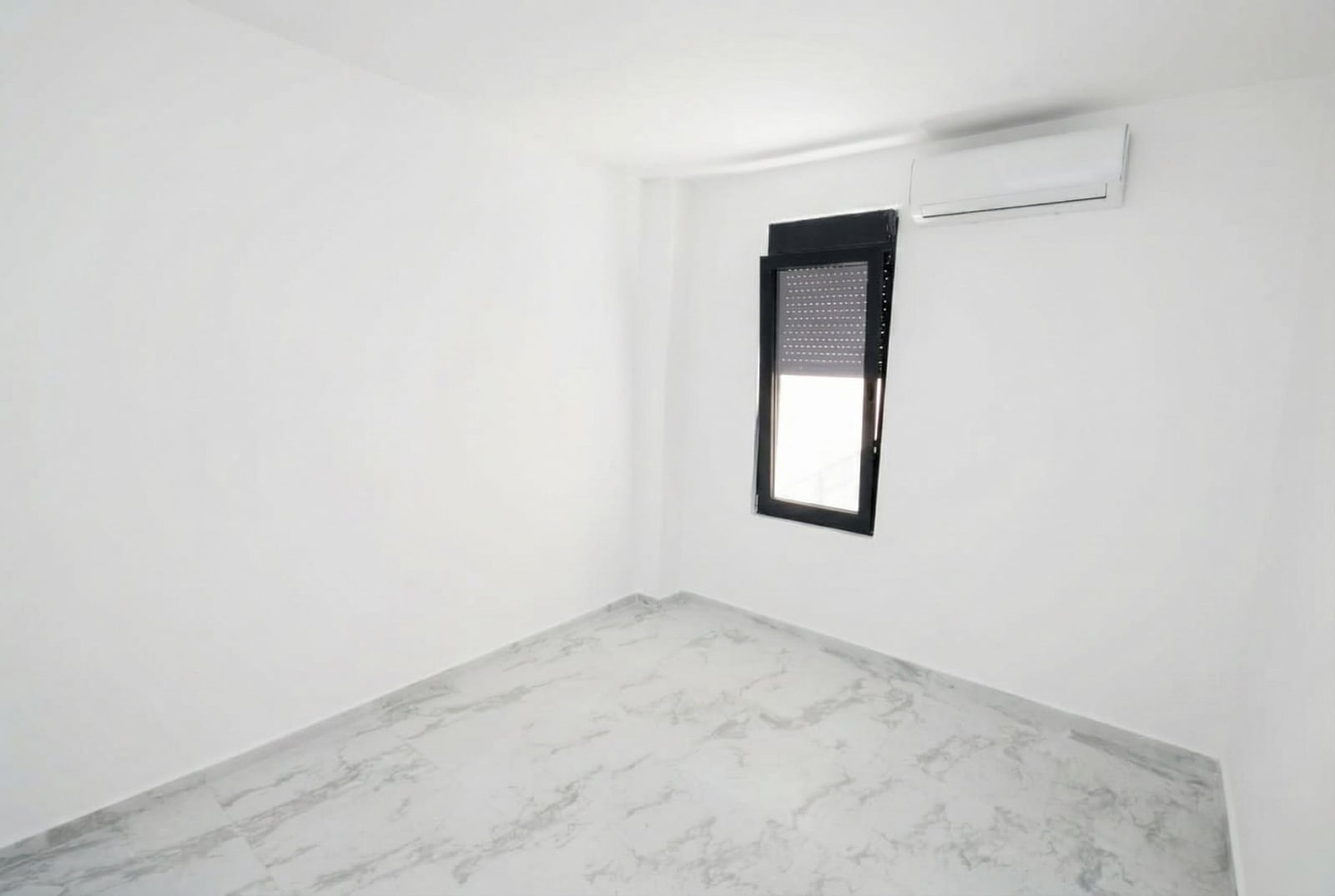 Bright bedroom with white finishes, marble flooring, and air conditioning in an apartment in Kumbor, Montenegro.