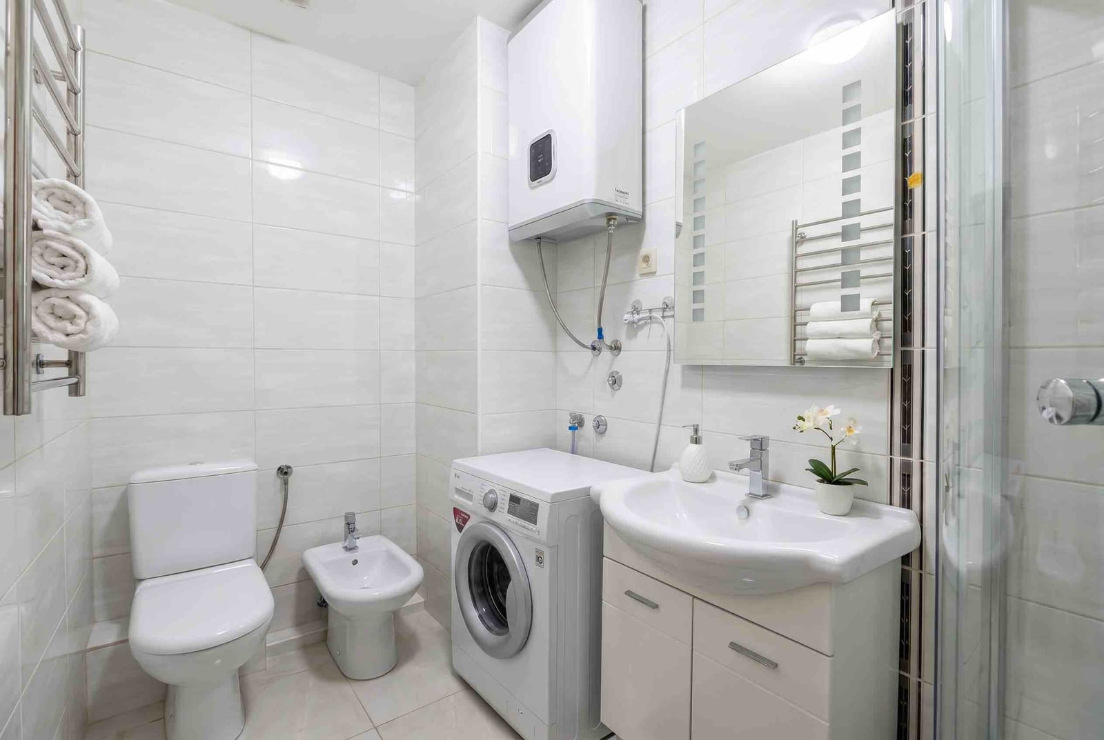 Modern bathroom in an apartment in Bečići, Montenegro: shower, washing machine, water heater, and white sanitary ware.