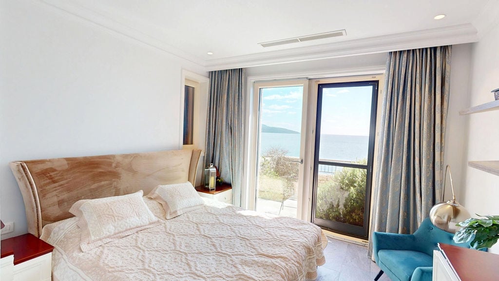 Bedroom with sea view in an apartment, Luštica, Montenegro: double bed, panoramic windows, and stylish interior.