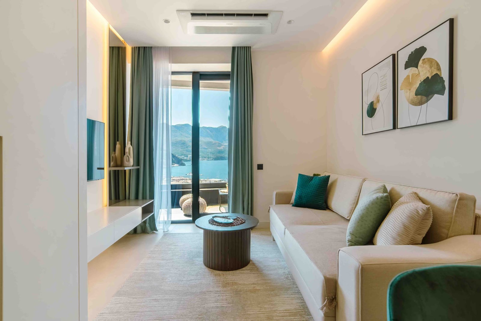 Living room in a modern apartment in Bečići, Montenegro: bright interior, sofa, sea and mountain view from the panoramic window.