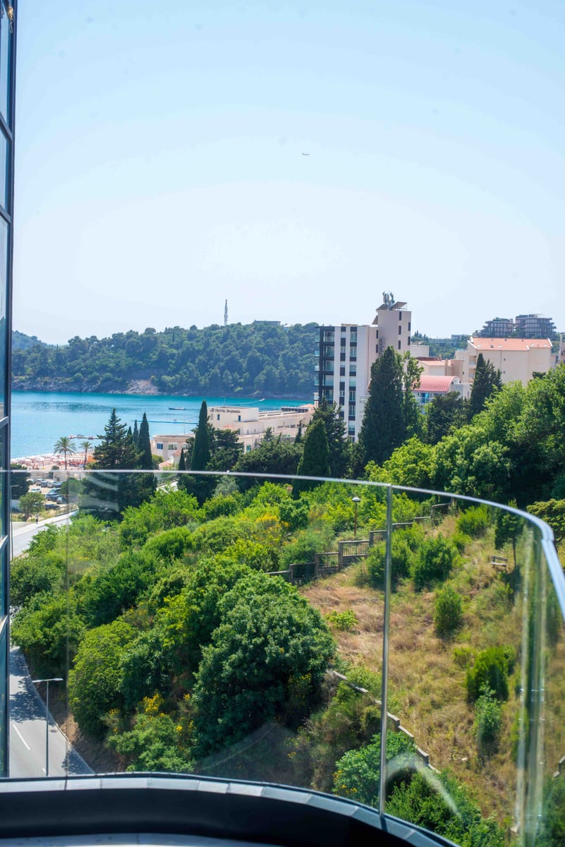View from the balcony of an apartment in Bečići, Montenegro: panorama of the sea, Splendid Hotel, green hills, and the beach.