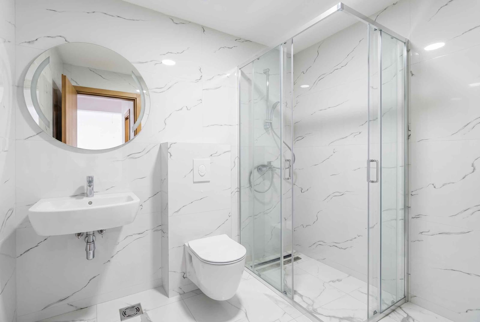 Modern bathroom in an apartment, Pržno, Montenegro: shower cabin, wall-hung toilet, and marble-look tiles.