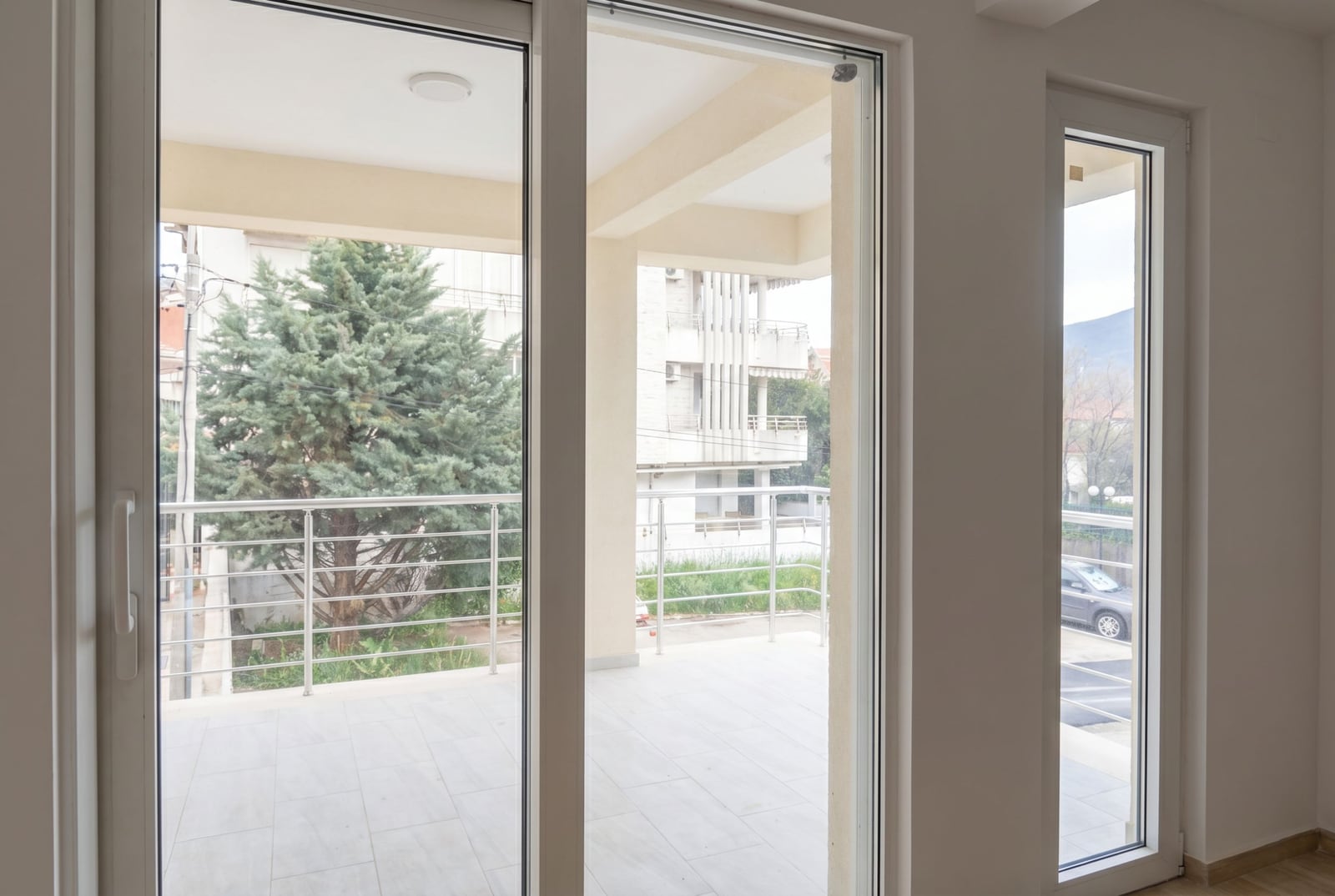 View from the living room onto a spacious terrace with a railing in an apartment in Herceg Novi, Montenegro.