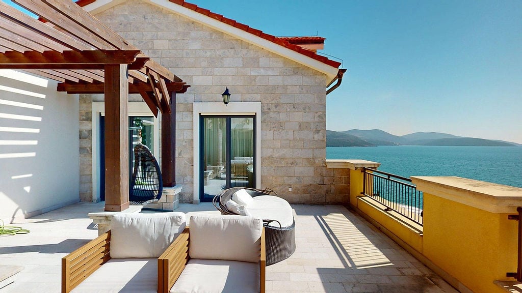 Terrace with furniture and sea view in the Luštica residential complex, Montenegro: stone finish and lounge area.