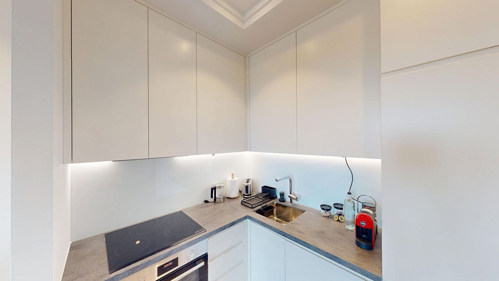 Modern white kitchen with lighting and built-in appliances in an apartment at Lustica Bay, Montenegro.