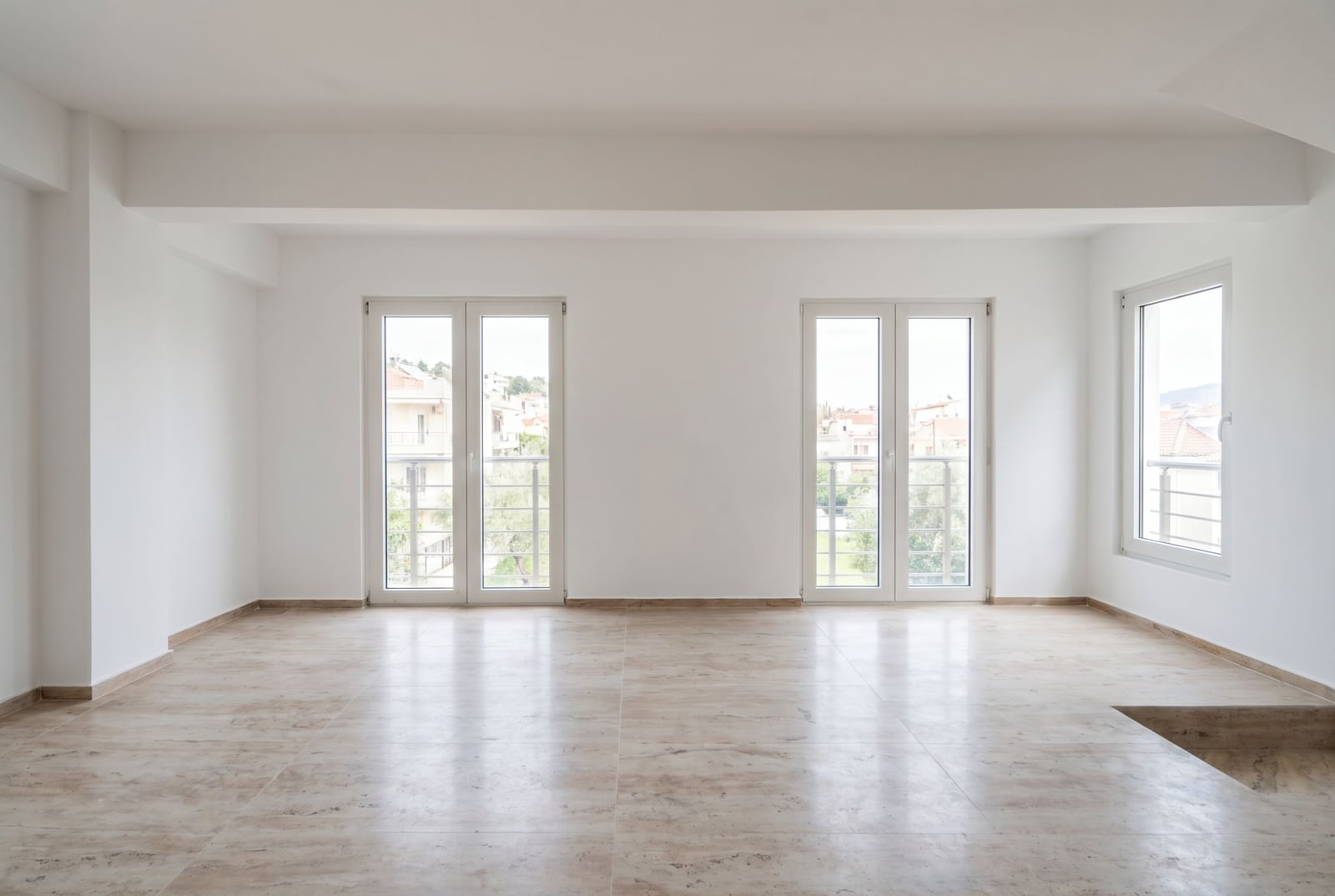 Bright living room in an apartment in Đenovići, Montenegro: white walls, tiled floor, and panoramic windows with city views.