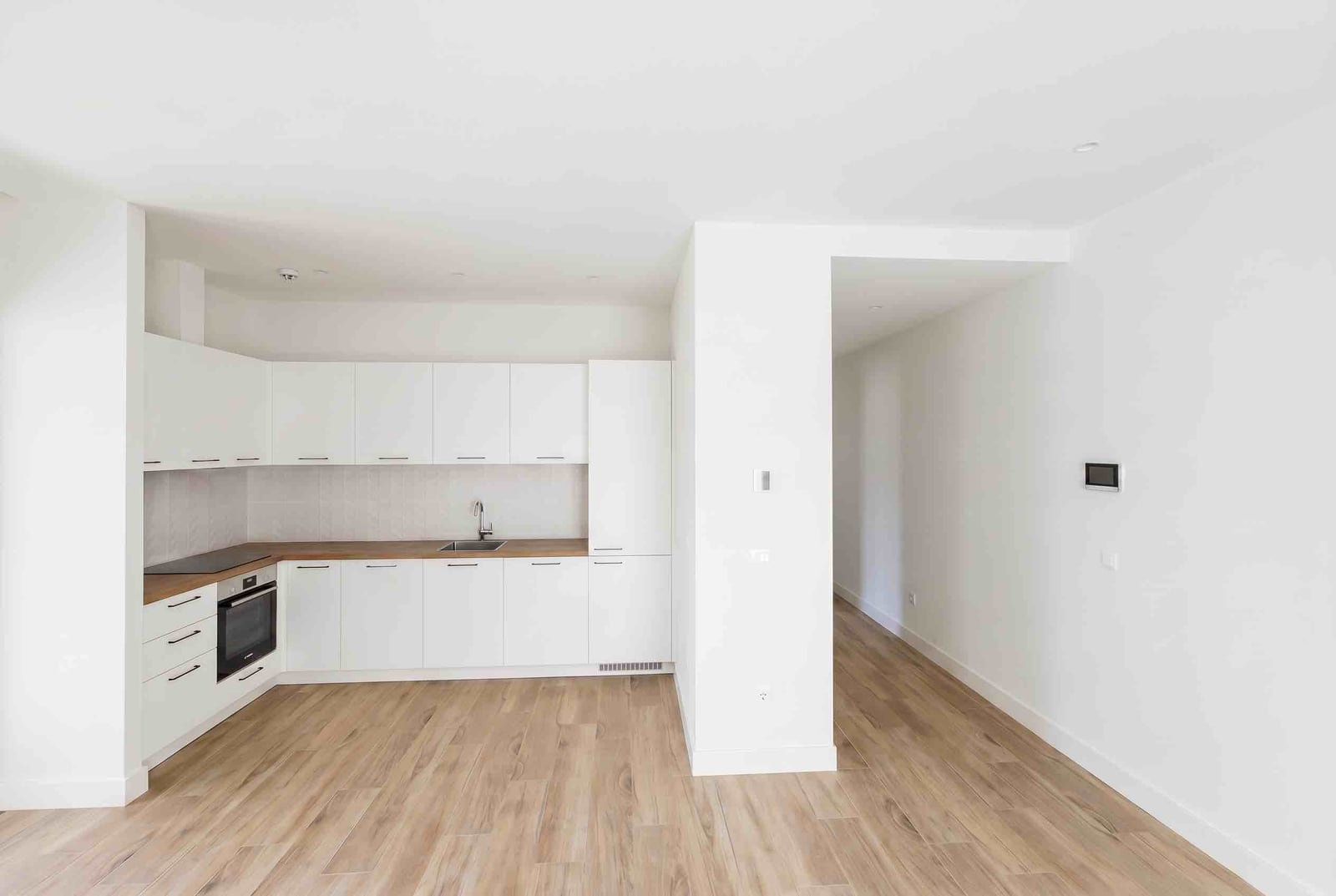 Modern white kitchen with a wooden countertop in a new apartment, Luštica Bay, Montenegro.