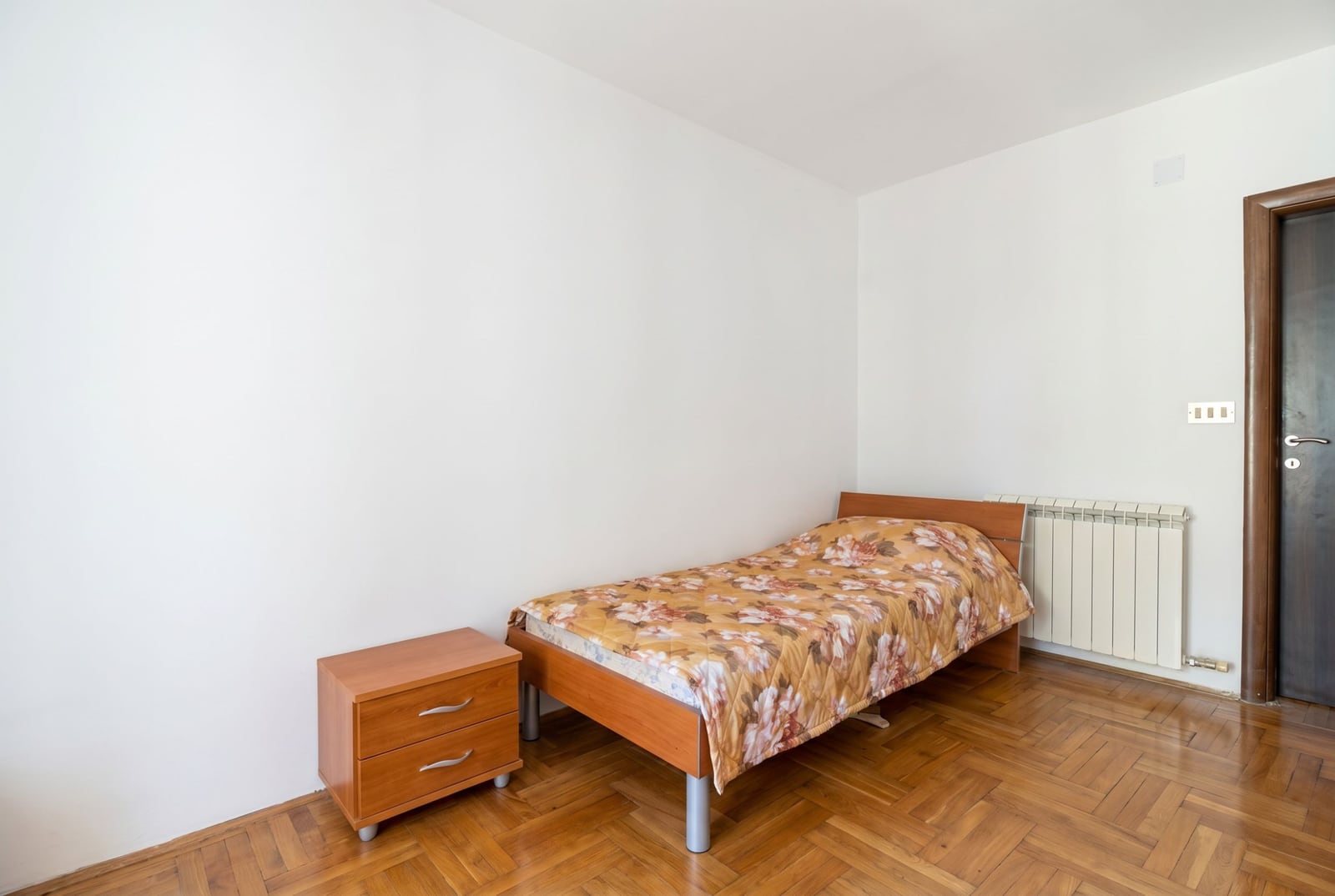 Bright bedroom with a single bed and parquet flooring in a house, Baošići, Montenegro. Cozy room with wooden furniture.