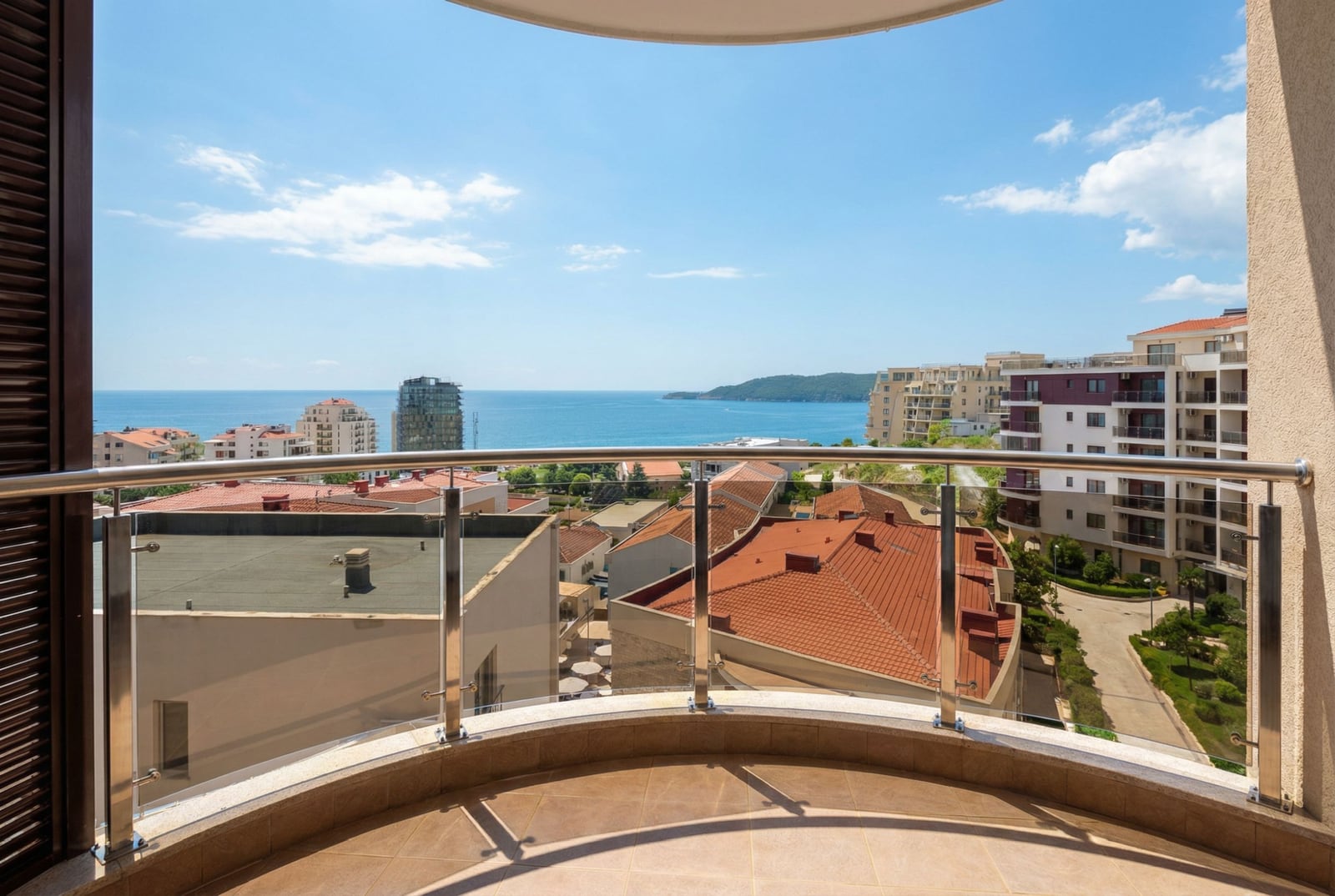 View from the apartment balcony in Rafailovići, Montenegro: sea panorama, tiled roofs, and the modern architecture of Bečići.