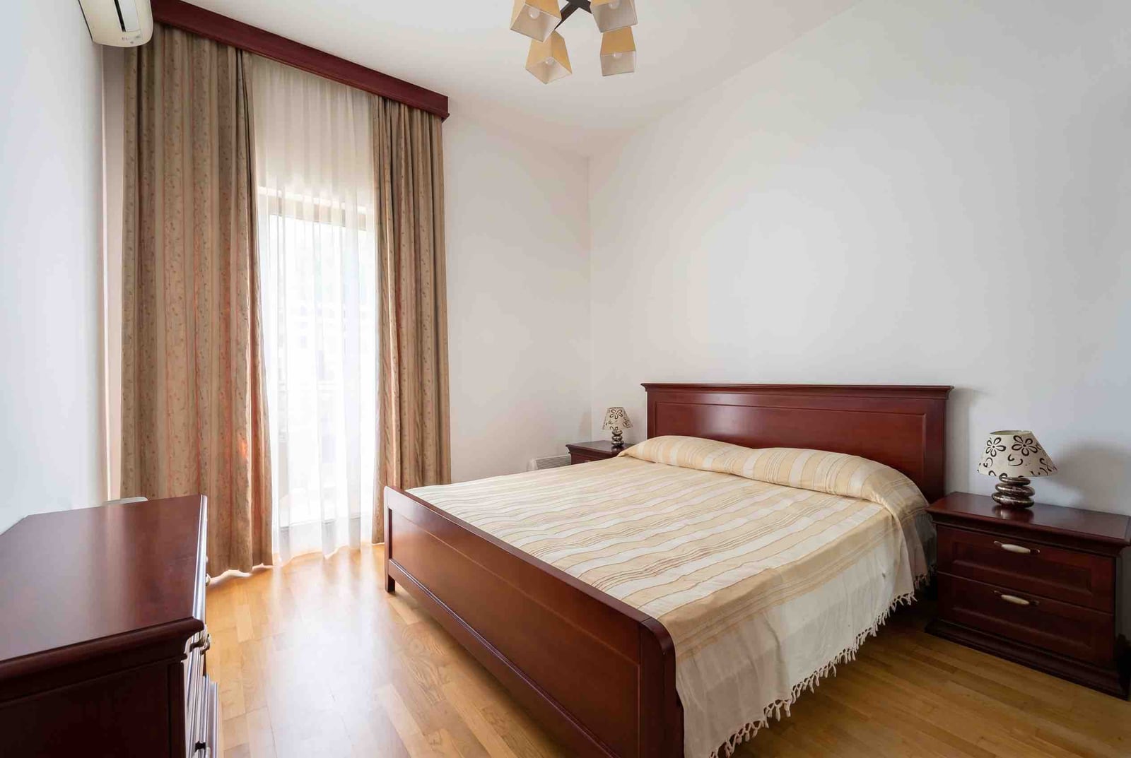 Cozy bedroom with a double bed and wooden furniture in an apartment, Bečići, Montenegro.