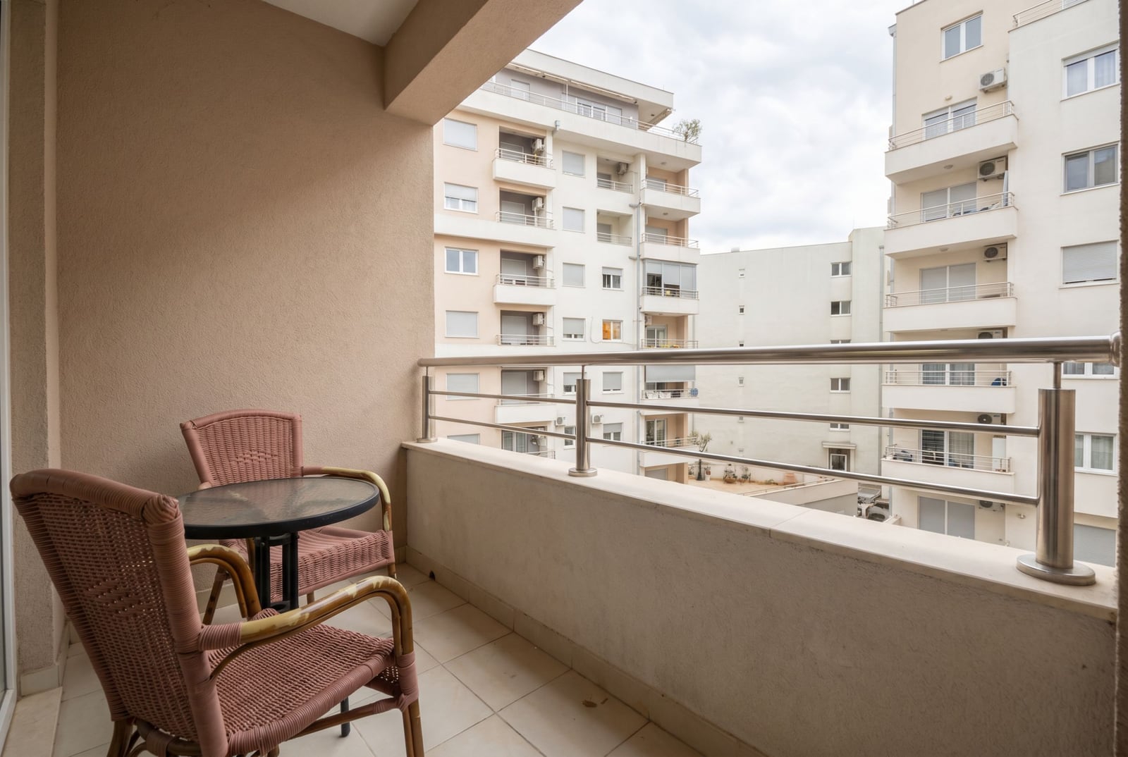Balcony with wicker furniture in an apartment in Budva, Montenegro: view of the residential complex and city buildings.