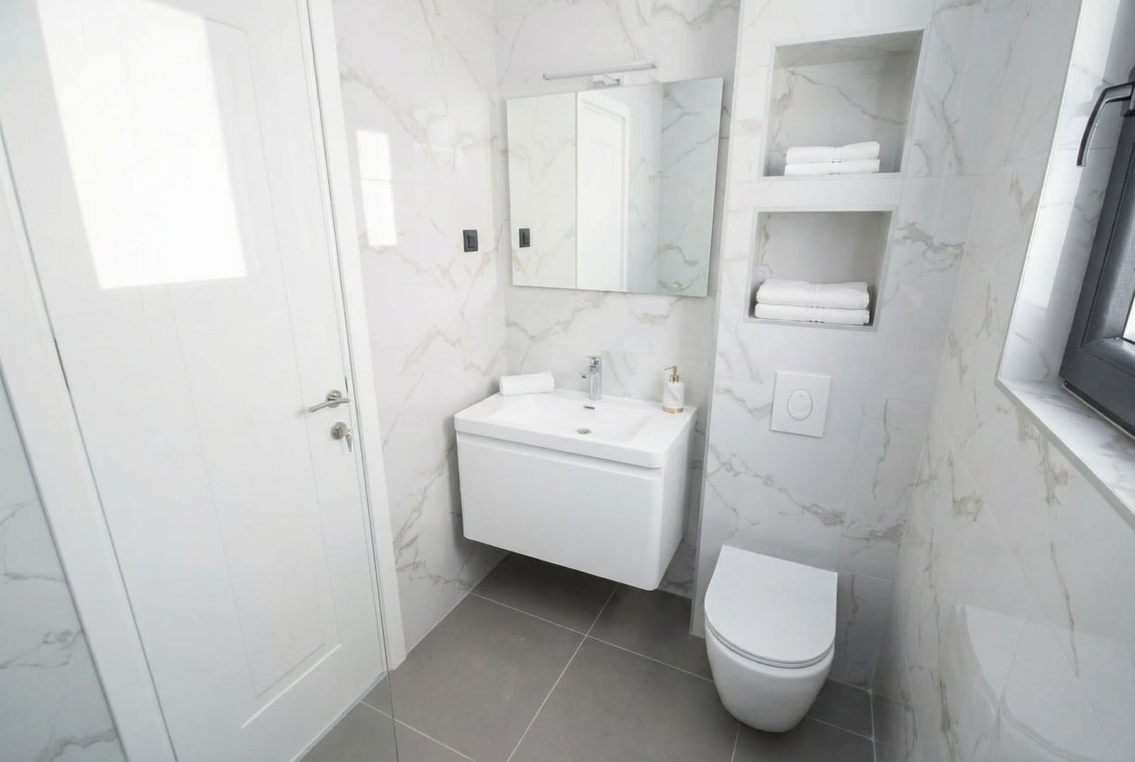 Modern bathroom with marble-style finishes in an apartment, Kumbor, Montenegro: wall-mounted sink and toilet.