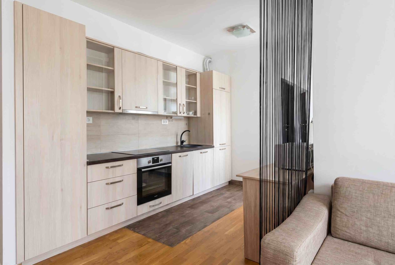 Modern kitchen with light-colored furniture and built-in appliances in an apartment in Budva, Montenegro.