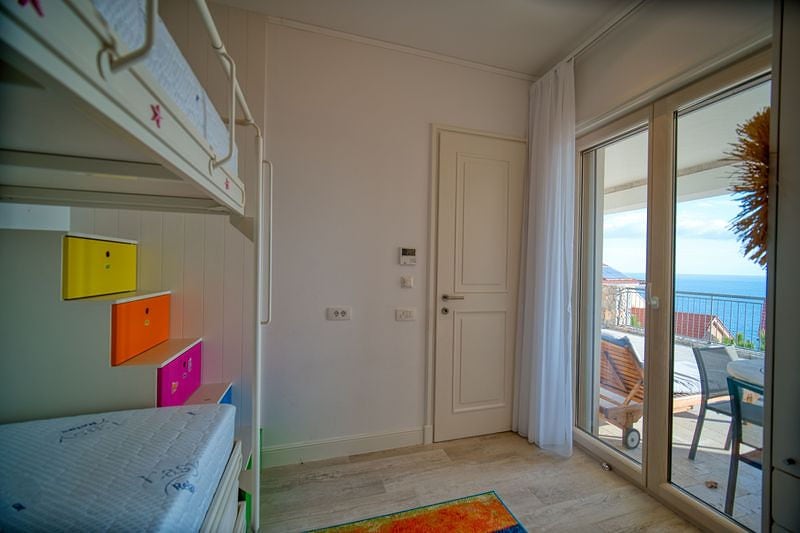 Children's bedroom with a bunk bed and access to a terrace with a sea view in an apartment, Luštica, Montenegro.
