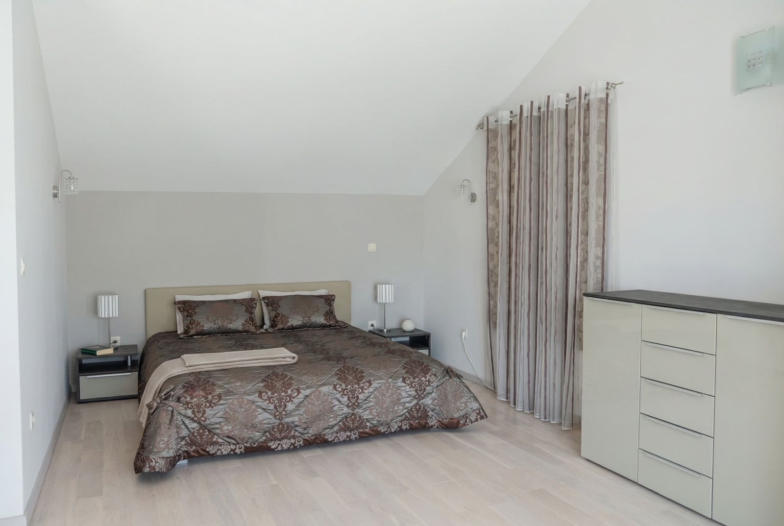 Bright bedroom with a double bed in a house in Herceg Novi, Montenegro: modern interior, sloped ceiling.