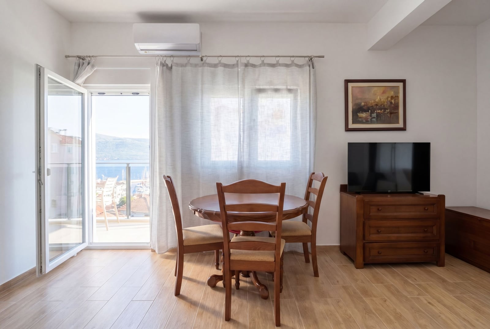 Living room with wooden furniture and access to a balcony with sea view in an apartment, Herceg Novi, Montenegro.