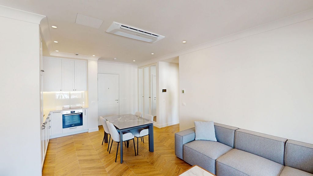 Modern living room with kitchen in Lustica Bay apartments, Montenegro: light interior, parquet flooring, built-in appliances.
