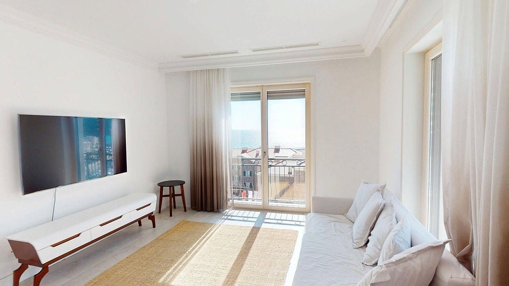 Bright living room in an apartment in Luštica, Montenegro: modern furniture, TV, panoramic windows with sea view.
