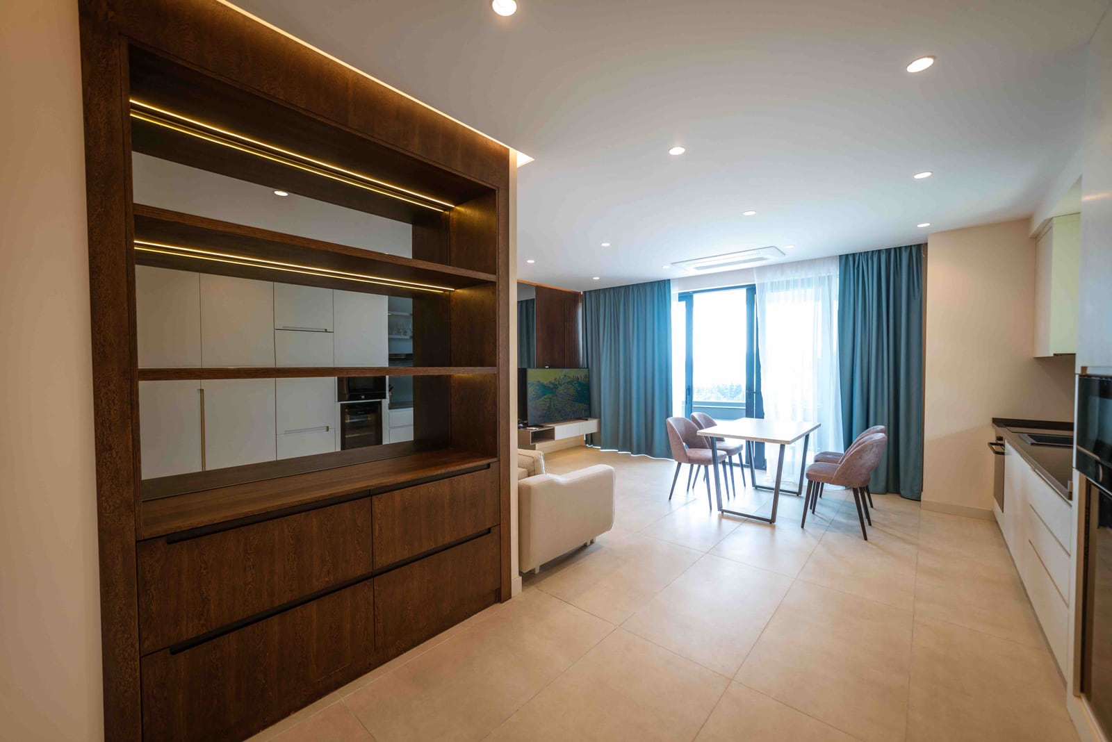 Modern living room with kitchen in an apartment in Bečići, Montenegro: stylish furniture, dining area, and panoramic windows.