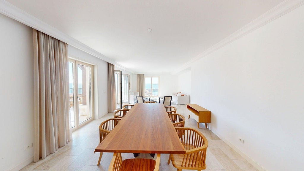 Bright living room with a dining area and sea view in an apartment, Luštica, Montenegro: wooden table and panoramic windows.
