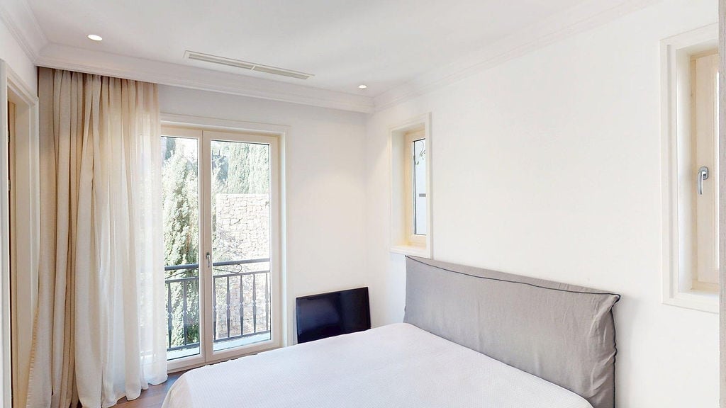 Bright bedroom in an apartment, Luštica, Montenegro: double bed, panoramic window with access to the balcony and garden view.