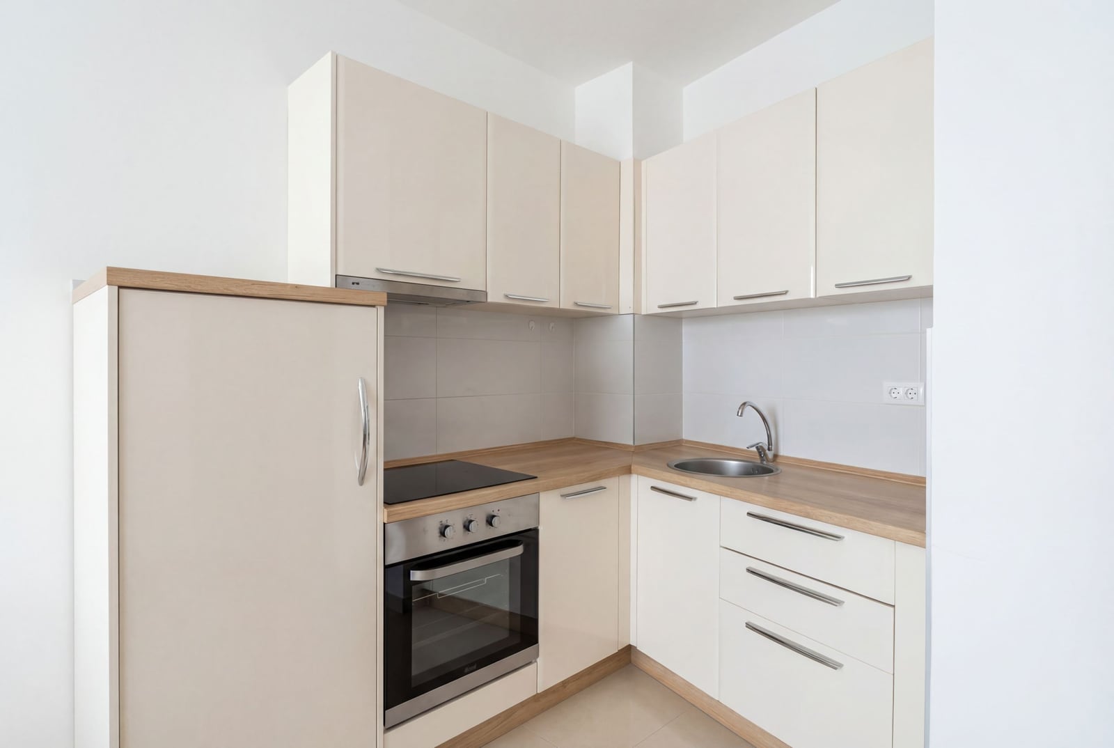 Modern bright kitchen in an apartment in Budva, Montenegro: built-in appliances, white cabinets, and a wooden countertop.