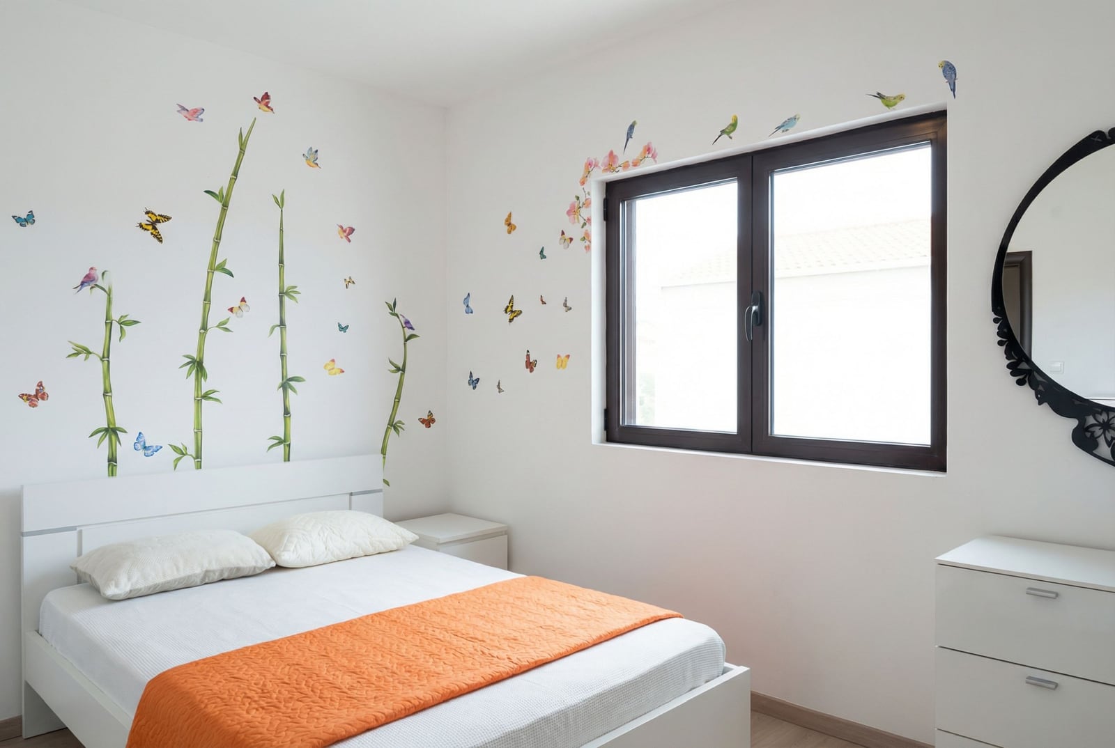 Светлая спальня в квартире в Бечичи, Черногория: белая мебель, оранжевое покрывало и декор стен с бамбуком и птицами.