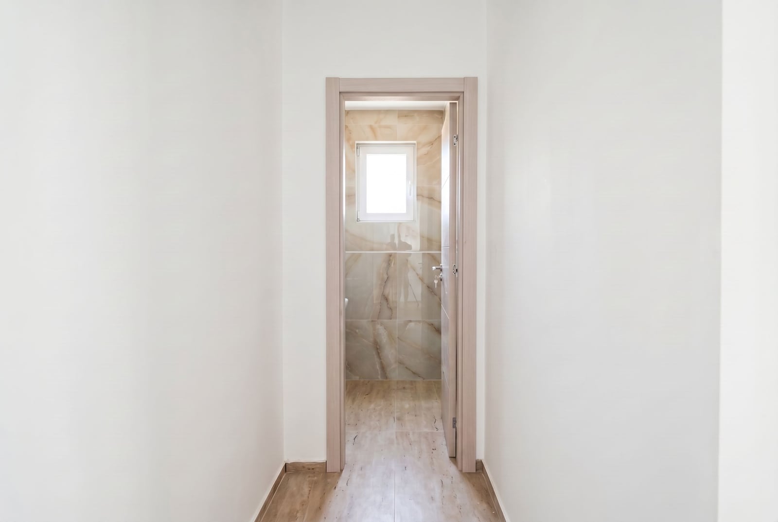 Entrance to the bathroom with beige marble-look tile finish in an apartment, Đenovići, Montenegro.
