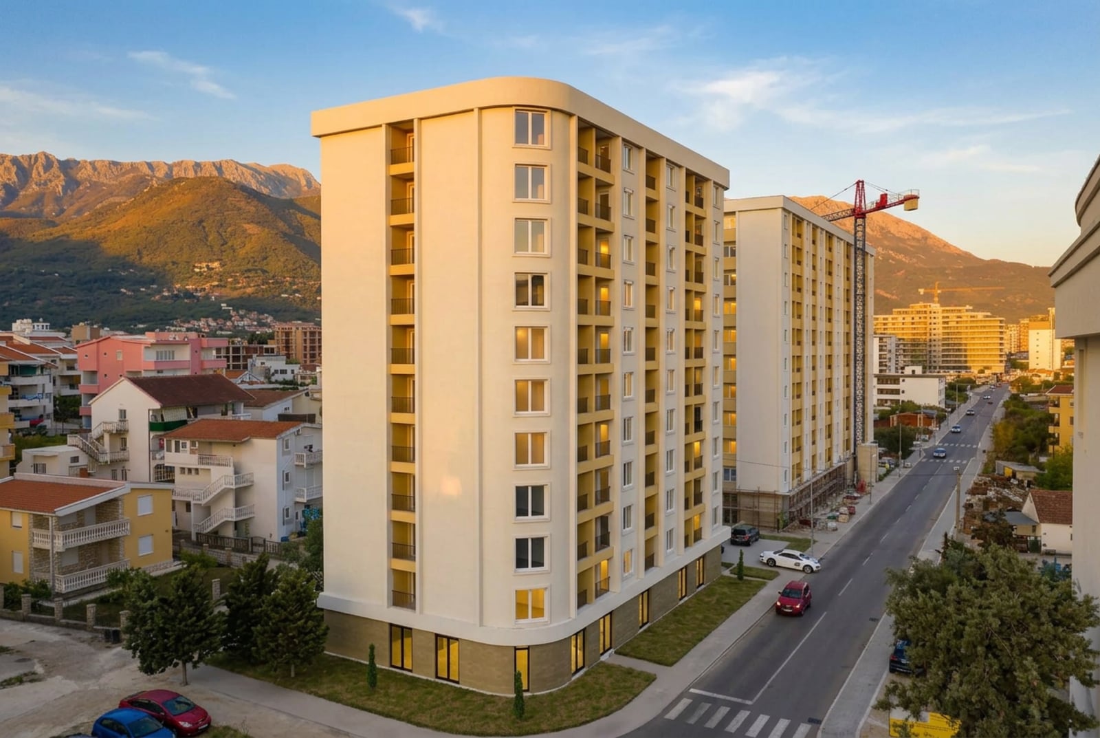 Karadağ’ın Bar şehrinde yeni bir konut kompleksi: dağlar fonunda balkonlu modern çok katlı bina.