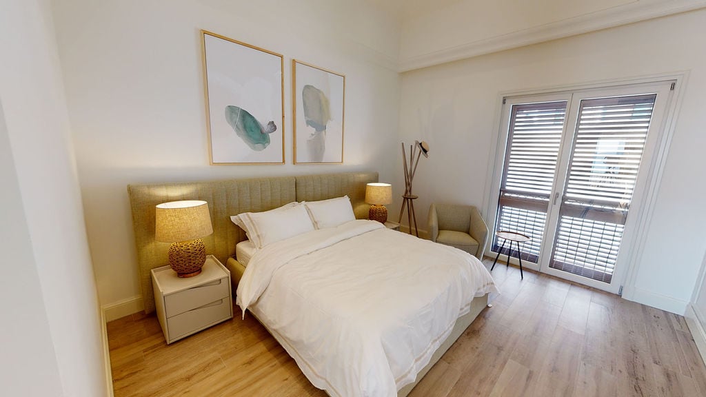 Bright bedroom with a double bed in the Luštica residential complex, Montenegro: modern interior, parquet flooring, and balcony access.
